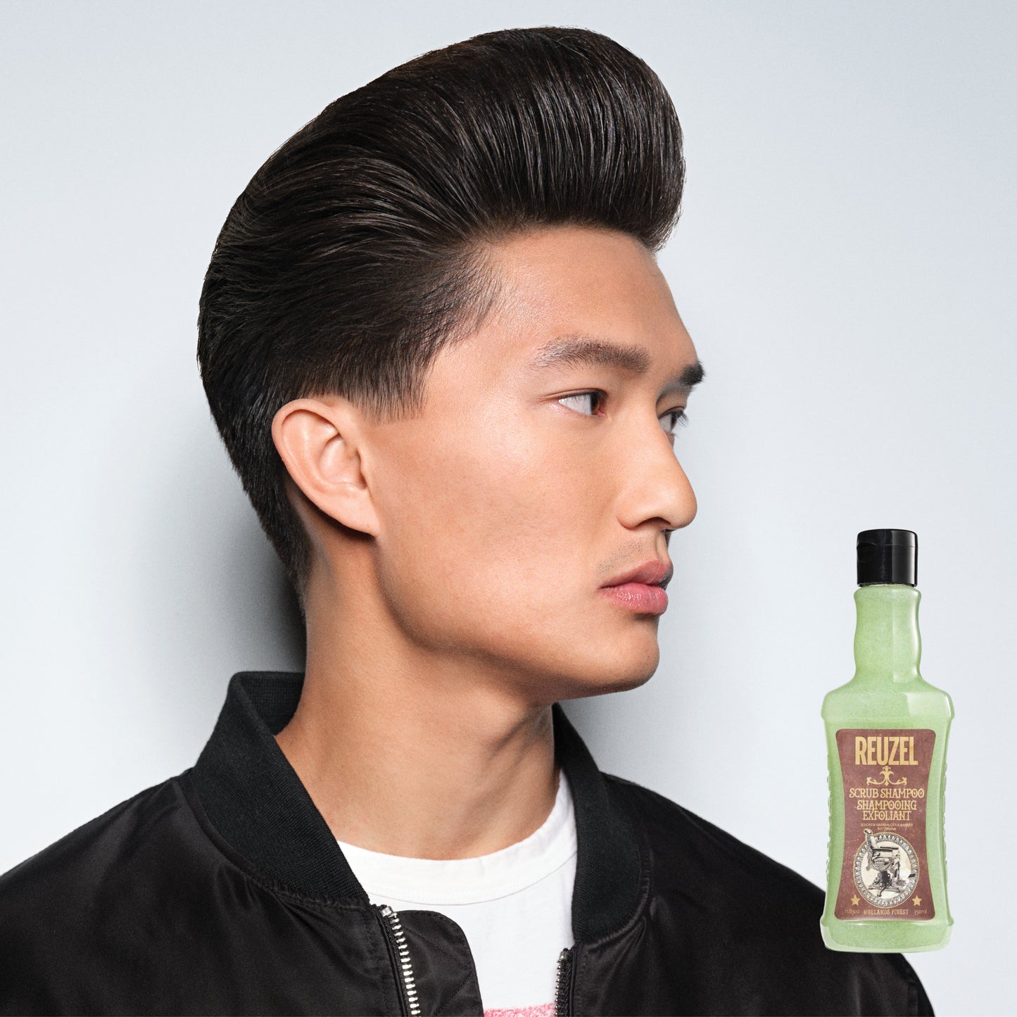Reuzel Scrub Shampoo bottle with label, showcasing a deep-cleansing haircare product in a sleek packaging design.